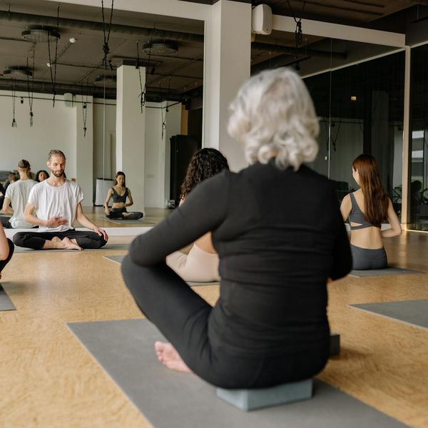 Group of diverse people sitting together on yoga mats in a bright studio.